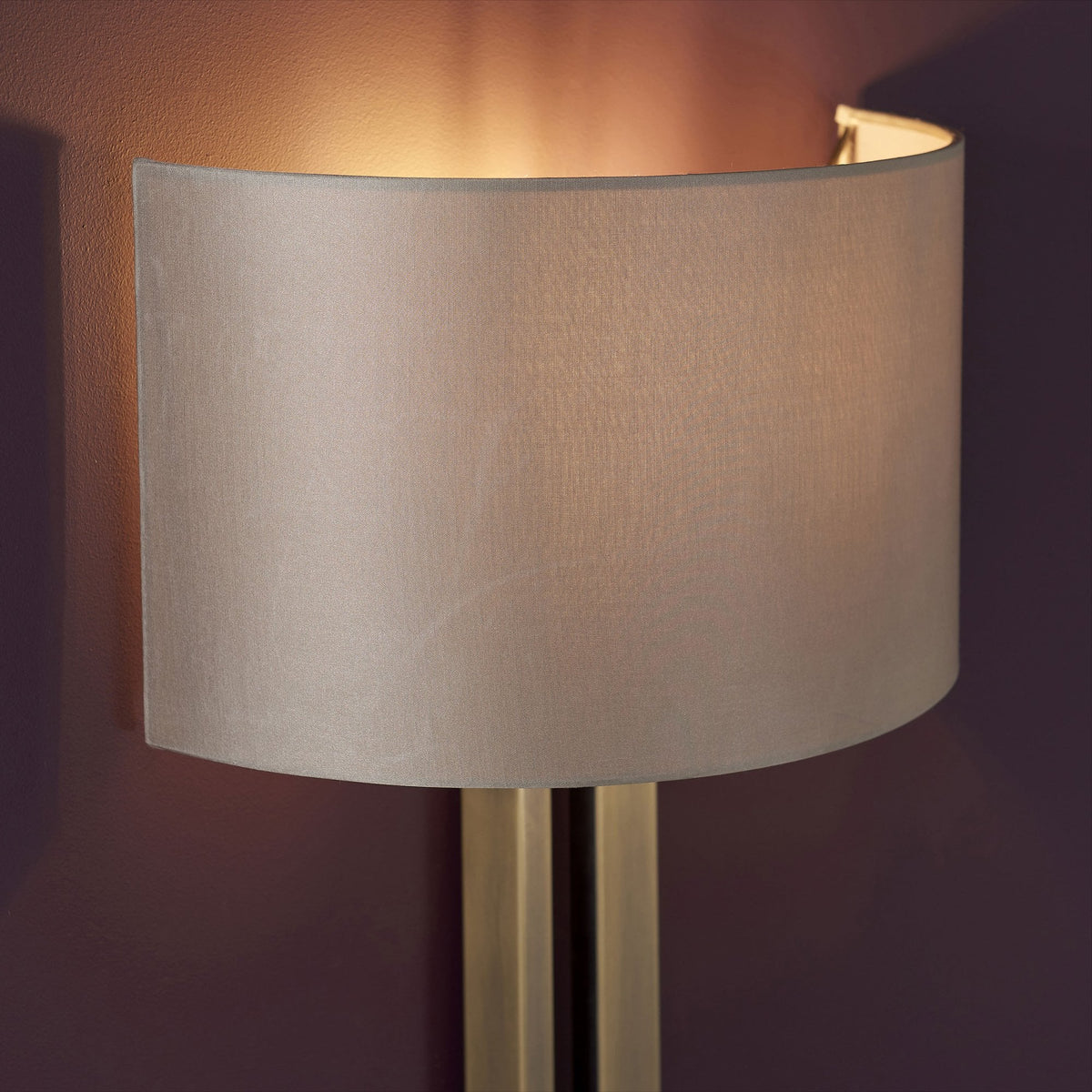 A close-up of the curved fabric shade of a wall light, casting a warm glow upwards.