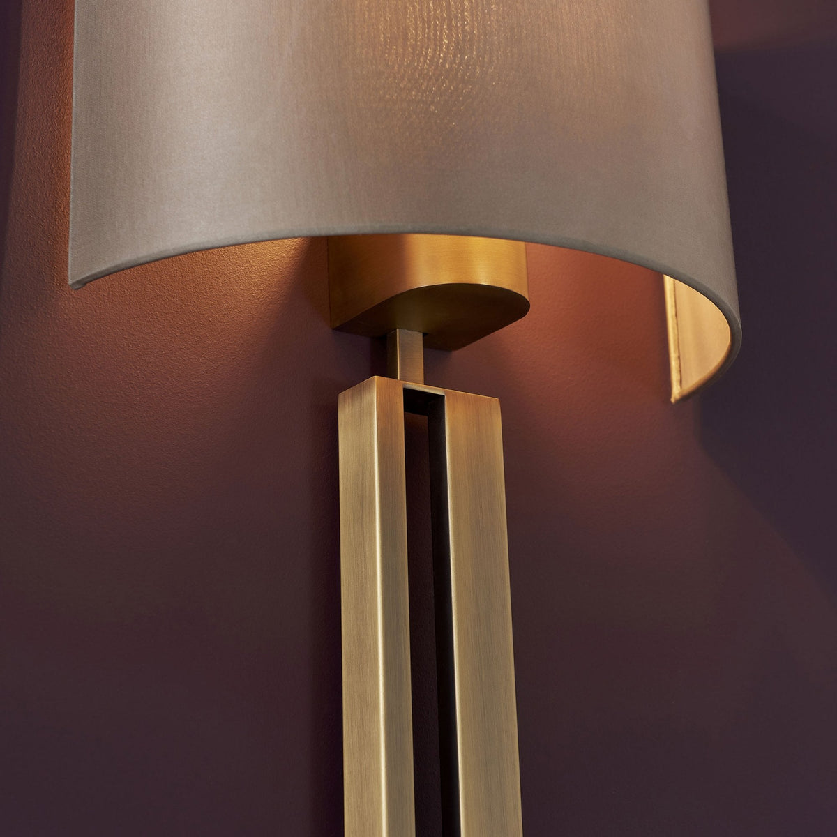 A detailed shot of the brass base and fabric shade connection of a stylish wall light.