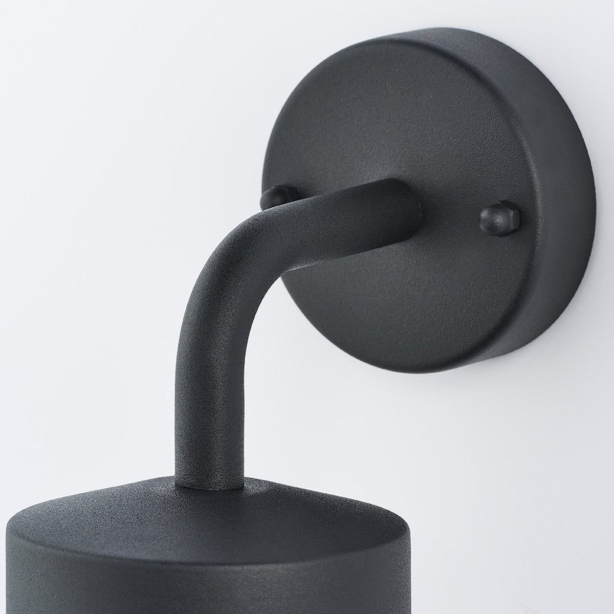 Close-up of the black wall mount and curved arm of an outdoor wall light.