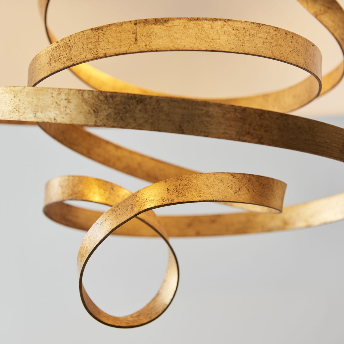 A detailed shot highlights the textured gold metal ribbons, forming an elegant, flowing design.