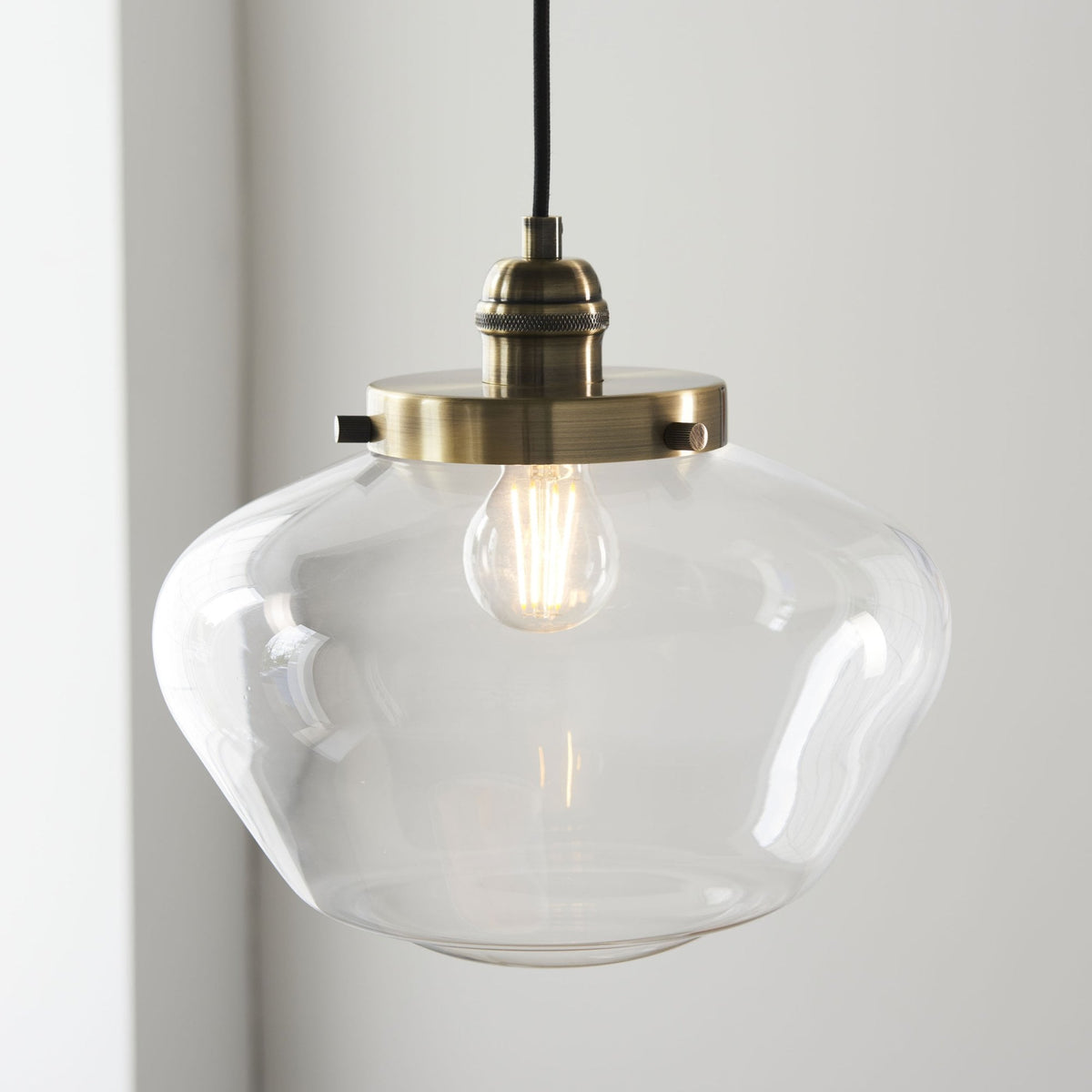 Close-up of a clear glass pendant light with a brass fixture and exposed bulb.