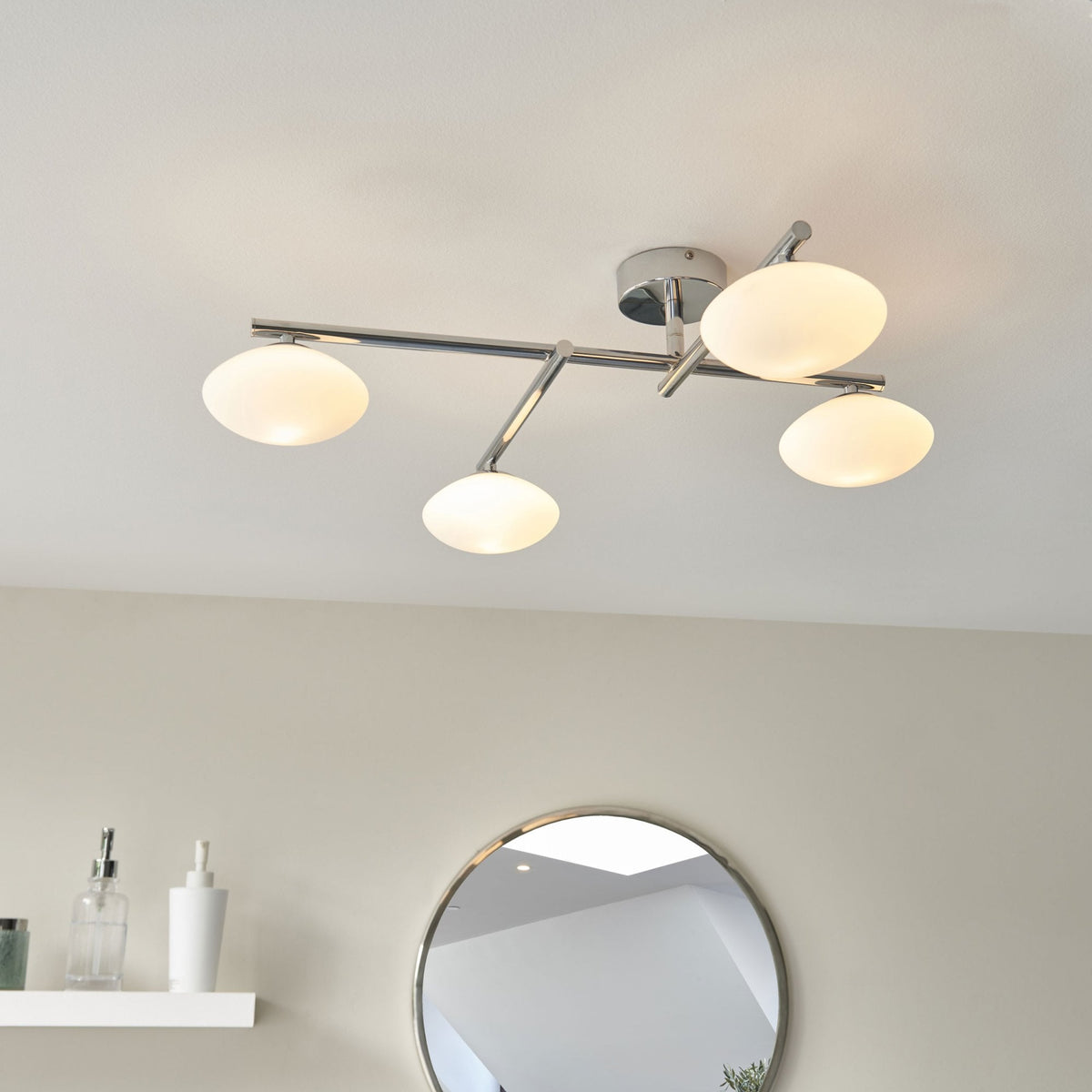 Four-light ceiling fitting with chrome finish and opal glass shades in a modern room.
