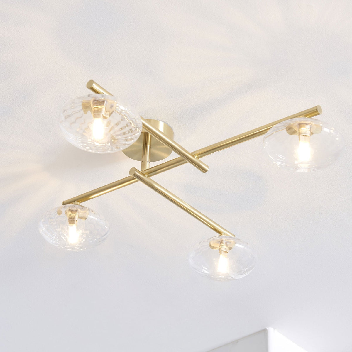 Four-light ceiling fixture with clear glass shades and brass arms.