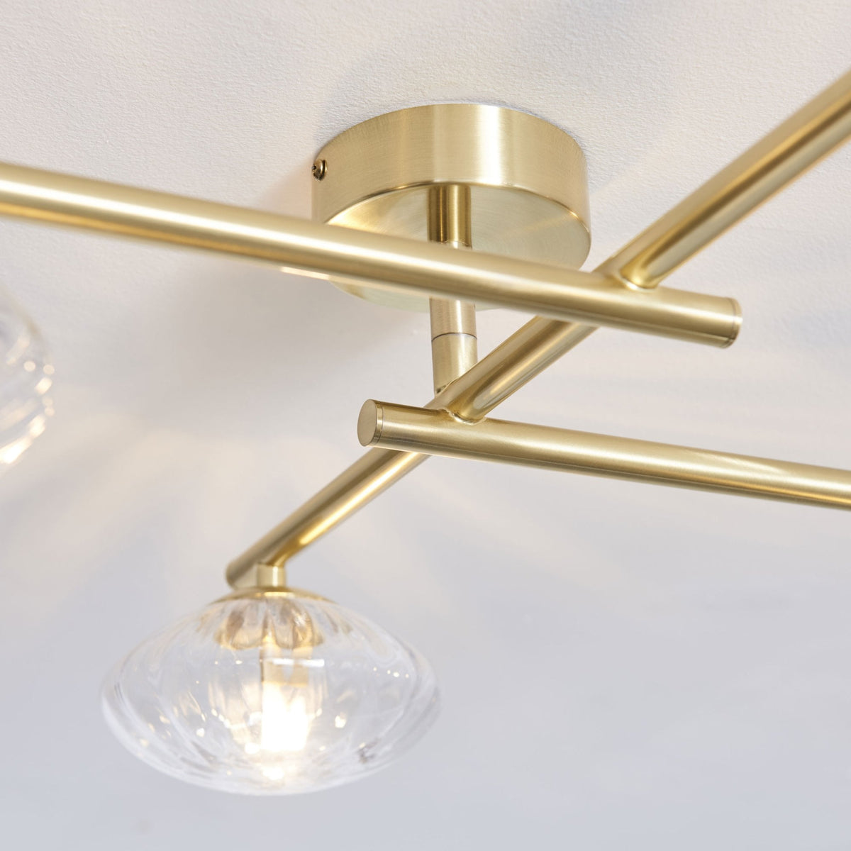 Close-up of a four-light ceiling fixture with clear glass shades and brass arms.