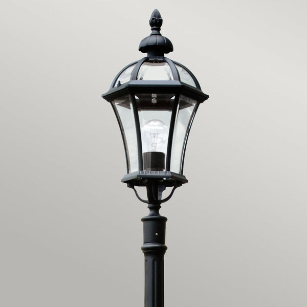 Close-up of a black street lamp's classic lantern head, showcasing its intricate details.