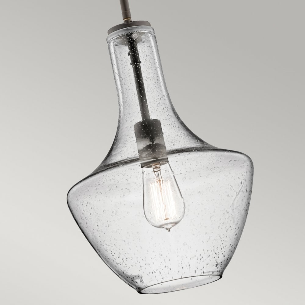 Close-up of the clear seeded glass shade and exposed bulb of the bronze pendant light.