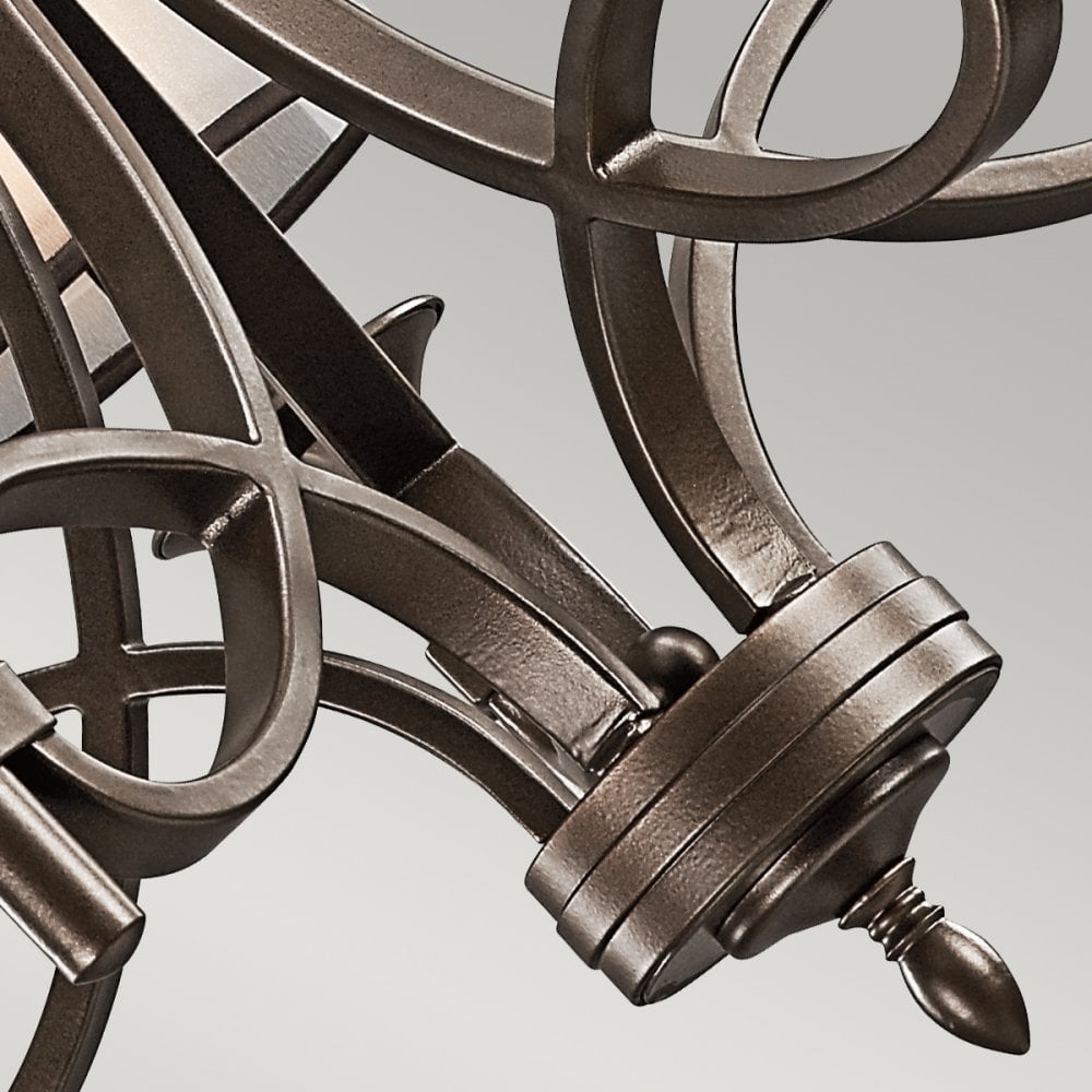 A close-up of the ornate dark bronze arms of a chandelier.