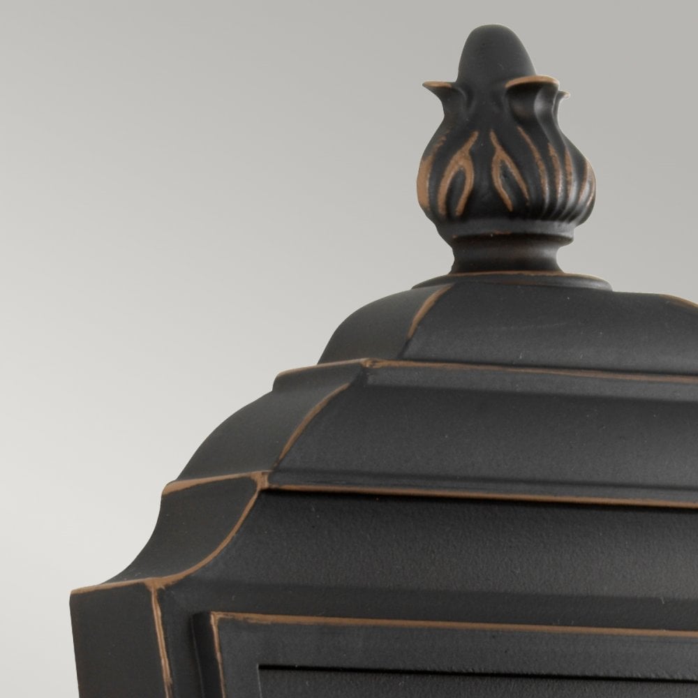 Top portion of the outdoor wall light, showing the decorative finial and weathered finish.