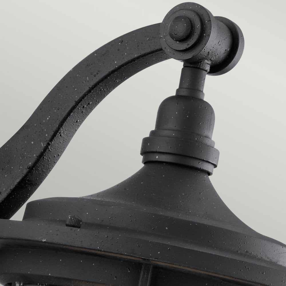A detailed view of the top arm and cap of the black outdoor wall light.