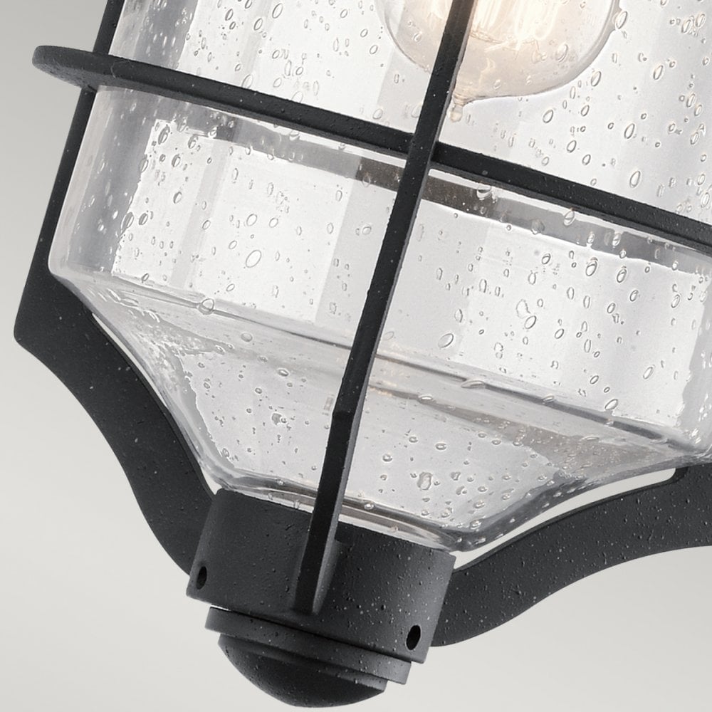 A detailed shot of the seeded glass and cage surrounding the bulb of the outdoor light.