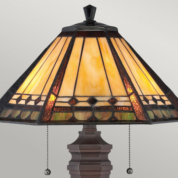 Close-up of a table lamp with an amber-toned geometric stained-glass shade.