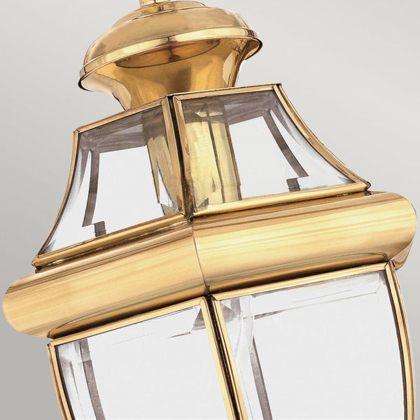A close-up of the upper section of a brass lantern with clear glass panels.