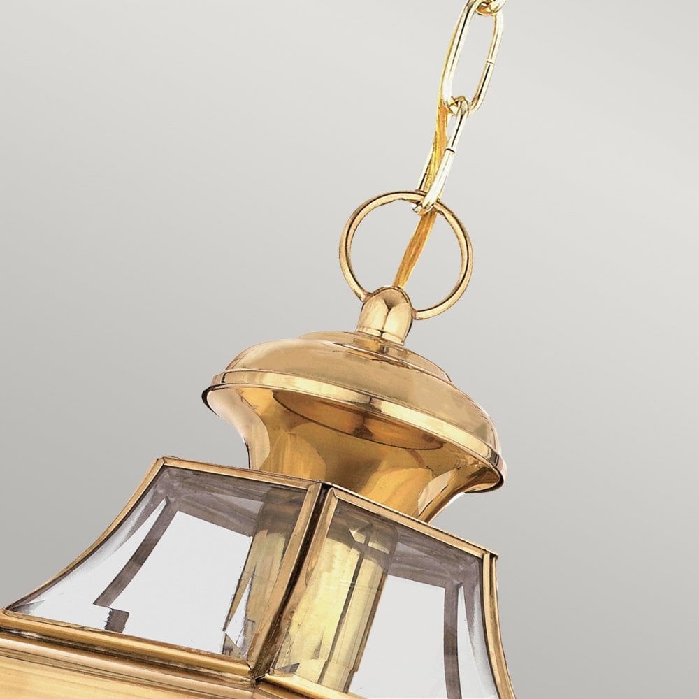 A close-up of the chain and top of a brass lantern with clear glass panels.