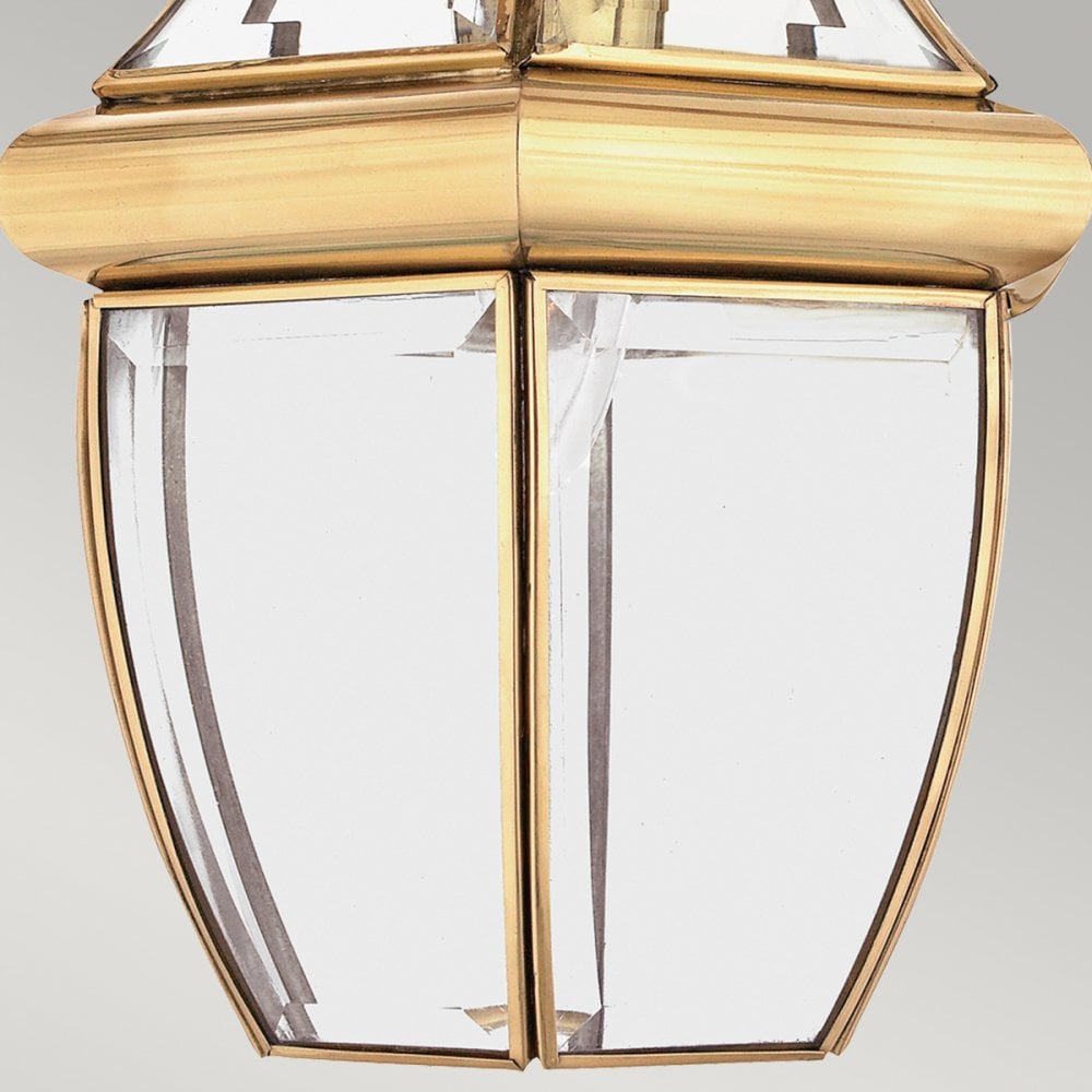 A close-up of the lower section of a brass lantern with clear glass panels.