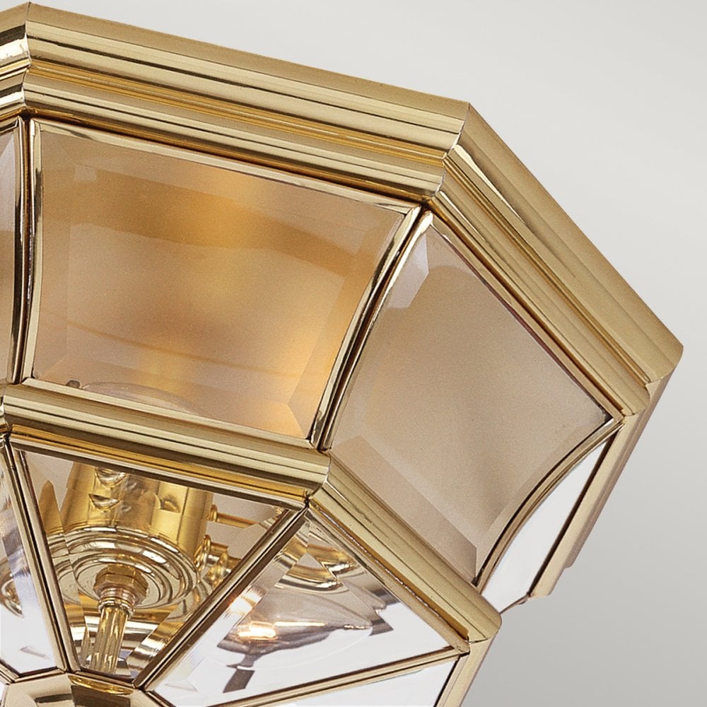 A close-up of the brass frame and frosted glass panels of the flush-mount ceiling light.