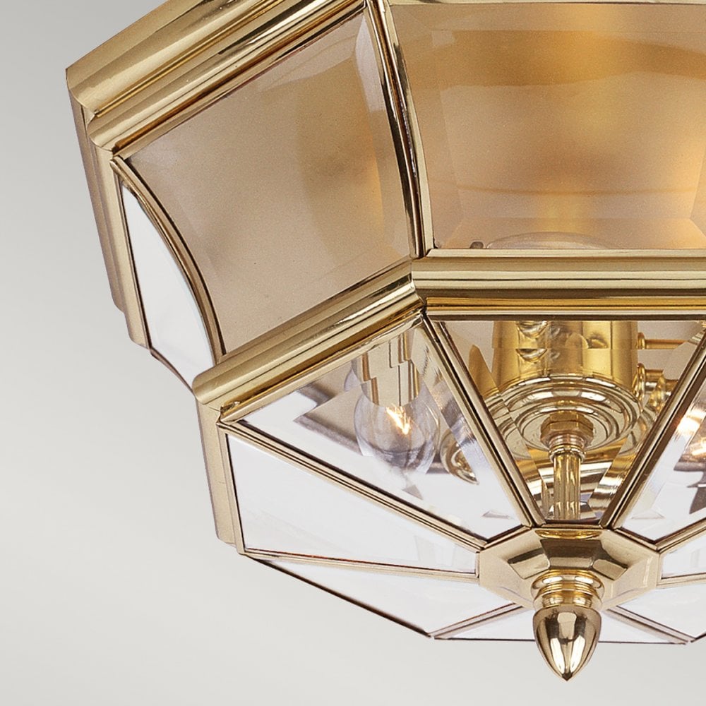 A close-up of the brass and clear glass panels of the flush-mount ceiling light.