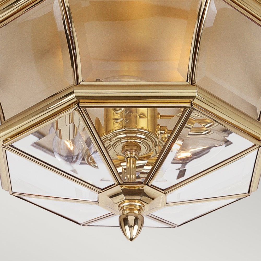 A close-up of the central brass finial and clear glass panels revealing lightbulbs.