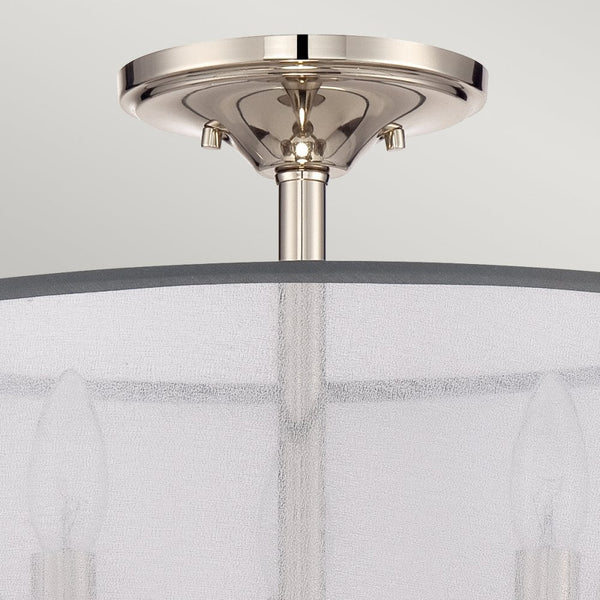 A close-up of the ceiling mount and top portion of a light fixture with a sheer shade.