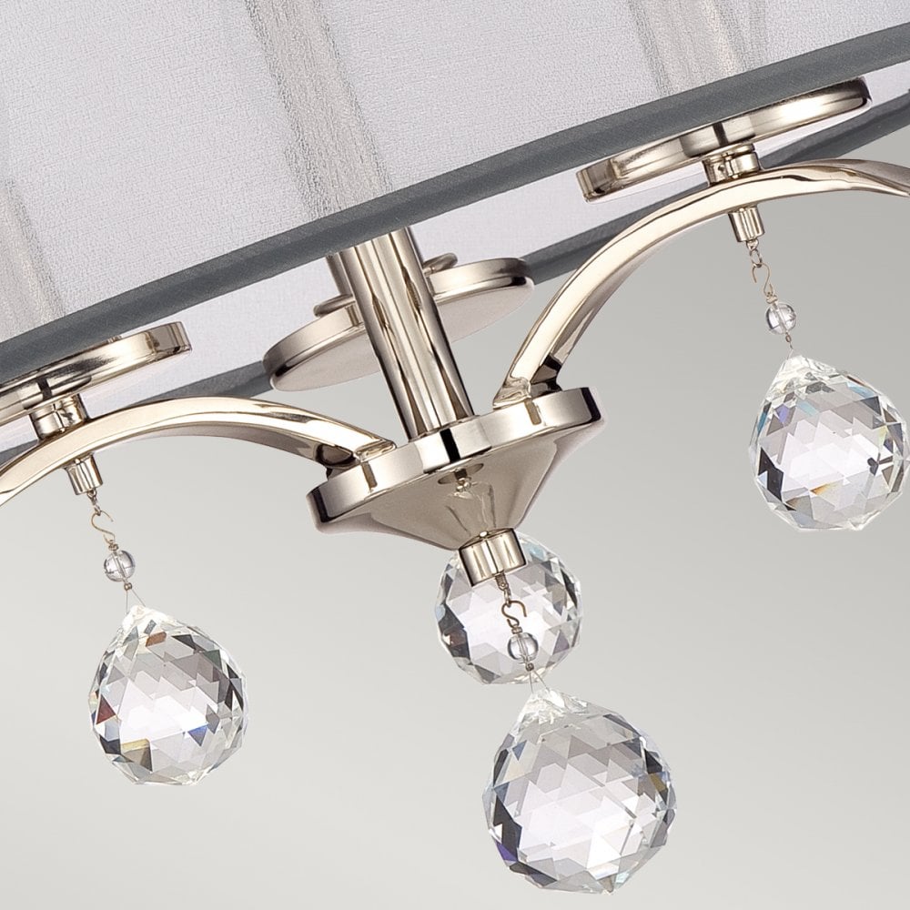 A detailed view of the polished nickel arms and sparkling crystal drops on a ceiling light.