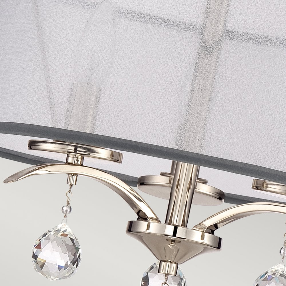 A close-up of the light fixture's polished nickel base, arching arms, and hanging crystals.