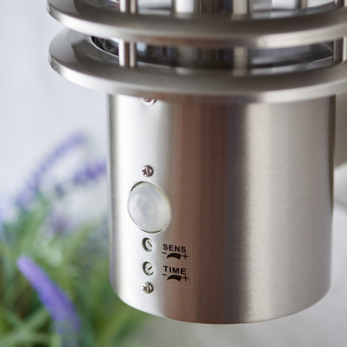Close-up of the motion sensor and settings on a brushed stainless steel outdoor wall light.