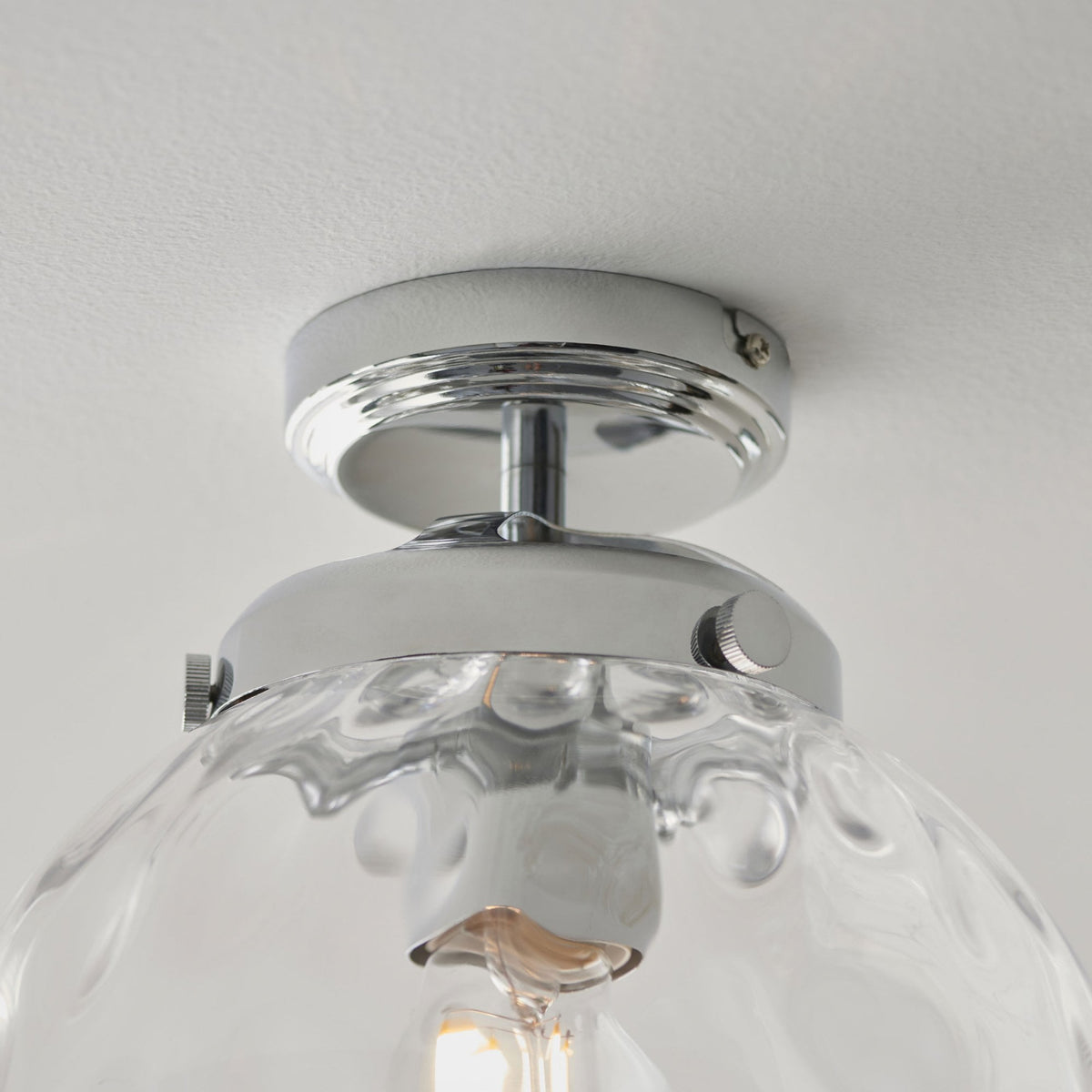 Close-up of the chrome base and textured glass of a ceiling light.