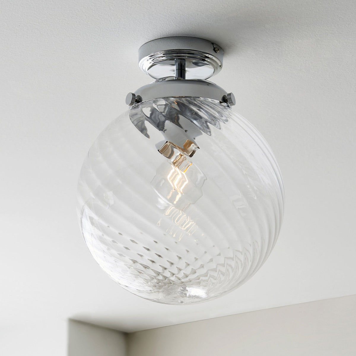 Clear glass globe ceiling light with a chrome base and a swirling pattern on the glass.