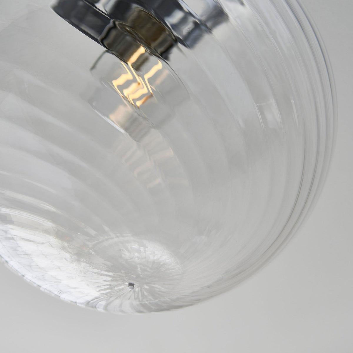 Close-up of the bottom of a clear glass globe ceiling light with a swirling pattern.