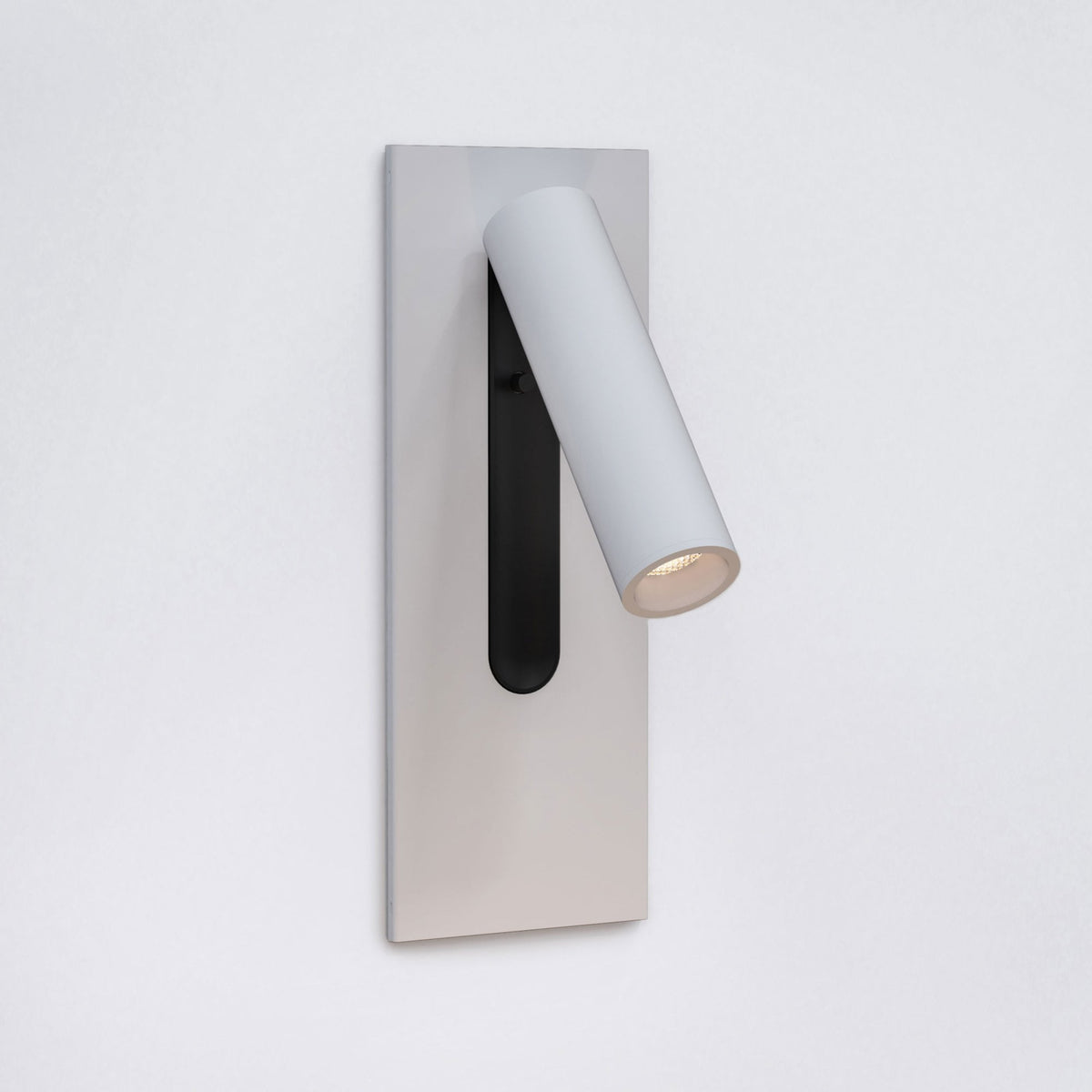 White wall-mounted light fixture with a cylindrical, adjustable light head pointing downwards