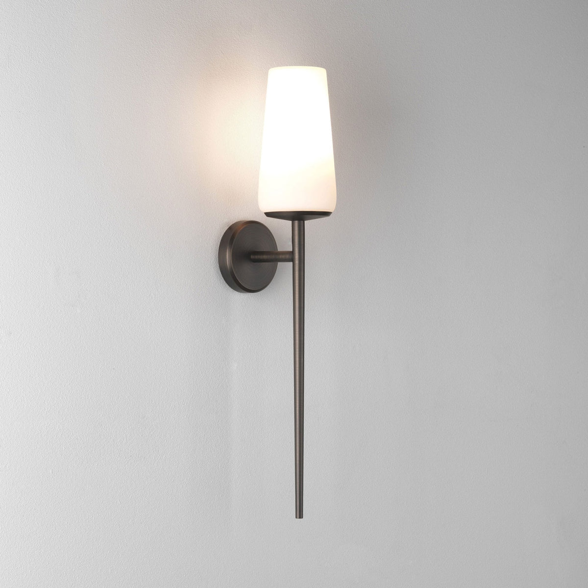 Wall-mounted sconce with a white conical shade and a dark bronze finish on a textured white wall
