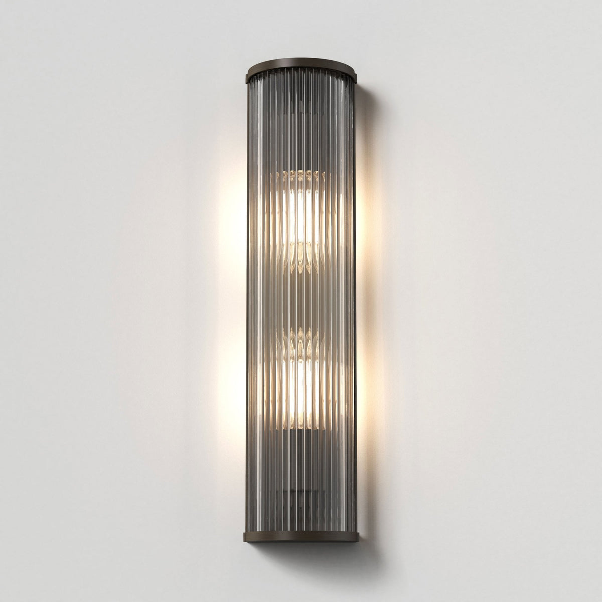 Rectangular wall sconce with fluted glass and bronze trim, emitting warm light