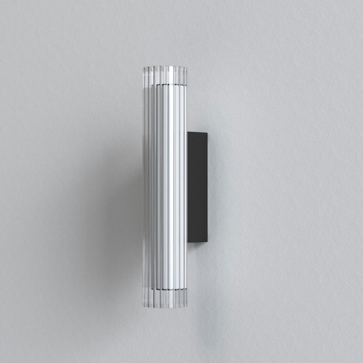 A cylindrical wall light with a clear ribbed glass shade and a black rectangular base