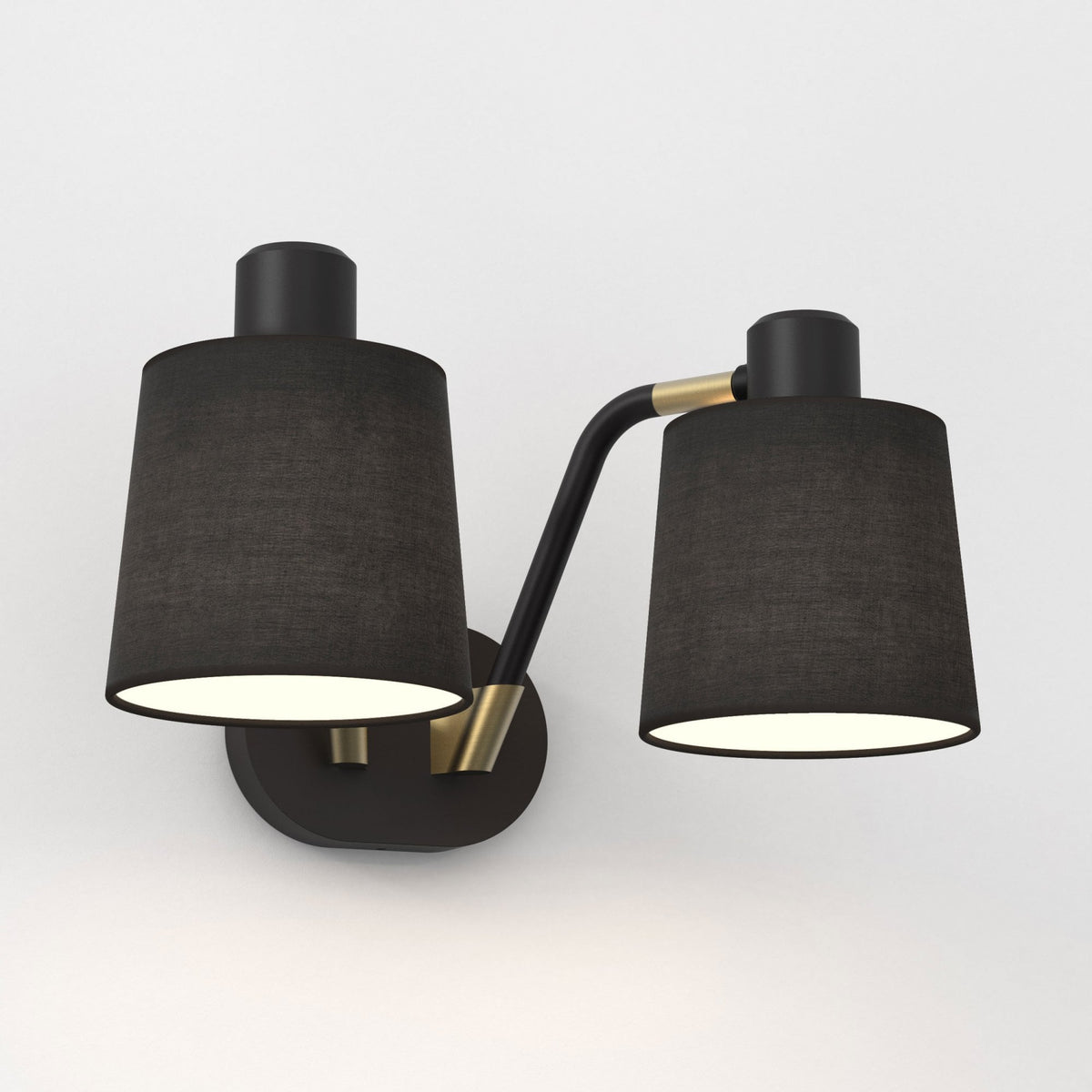 Black wall sconce with two conical fabric shades and brass accents