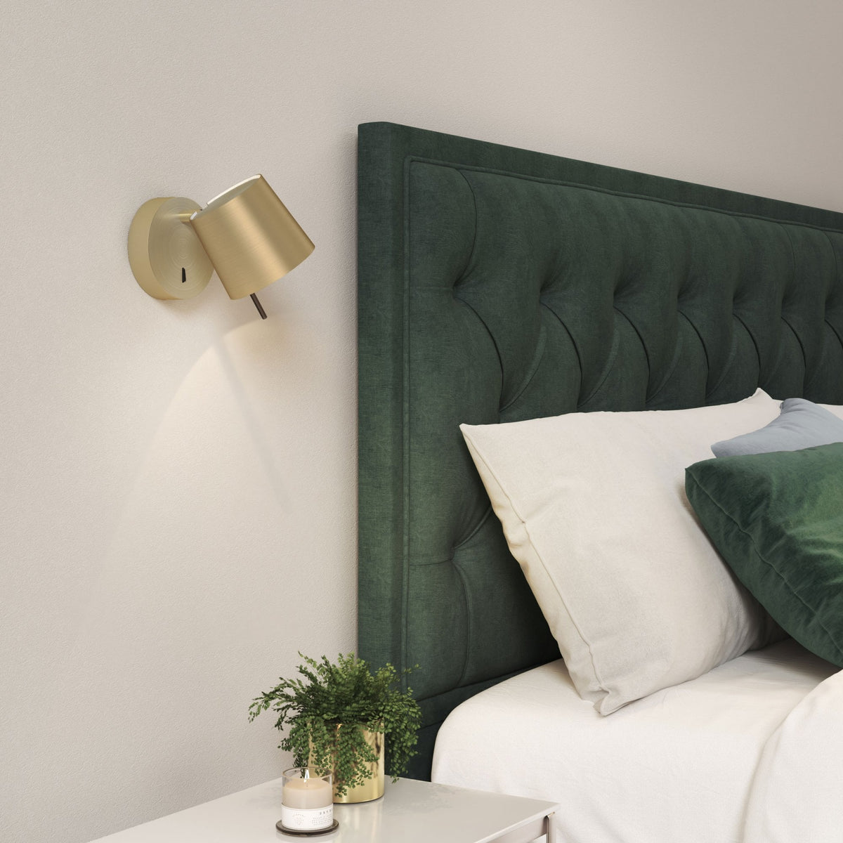 Bedroom with green tufted headboard, gold wall lamp, white bedding, and a plant on a nightstand