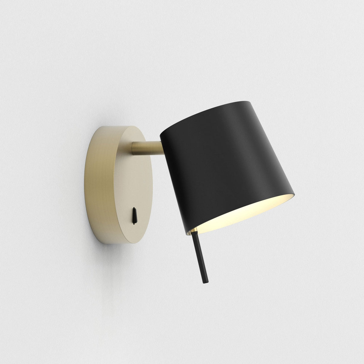 Black and gold wall lamp with a conical shade, angled downwards, emitting a warm glow