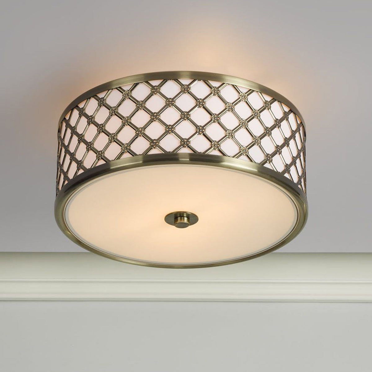 Antique brass flush mount light with a decorative lattice pattern around the drum shade.
