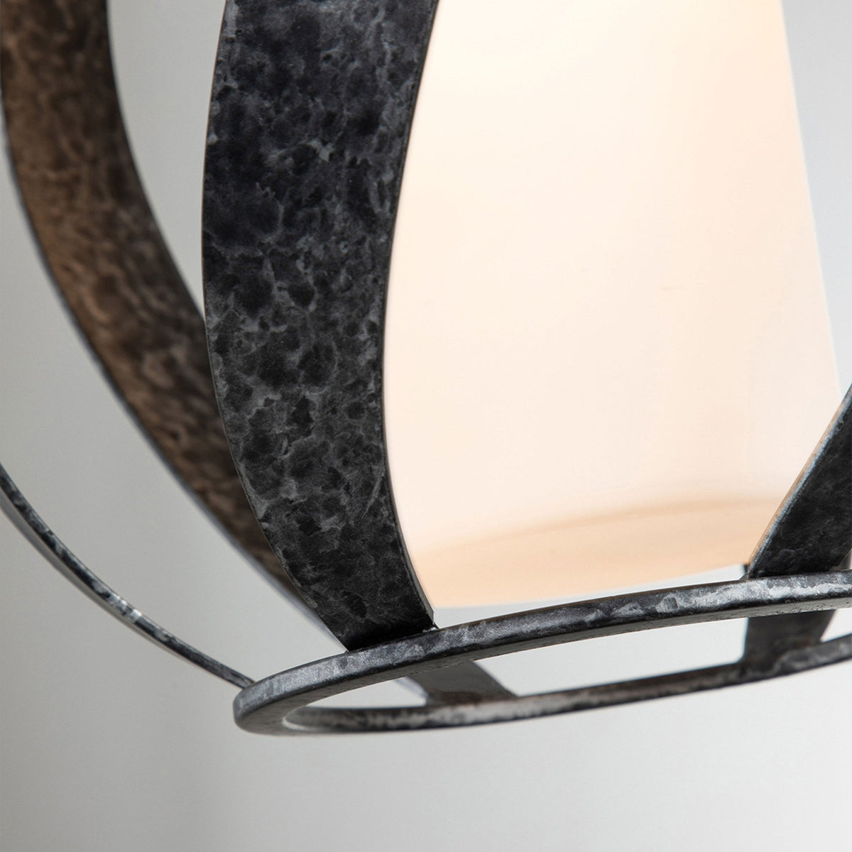 A detailed view of the frosted glass diffuser and aged metal cage of the wall light.