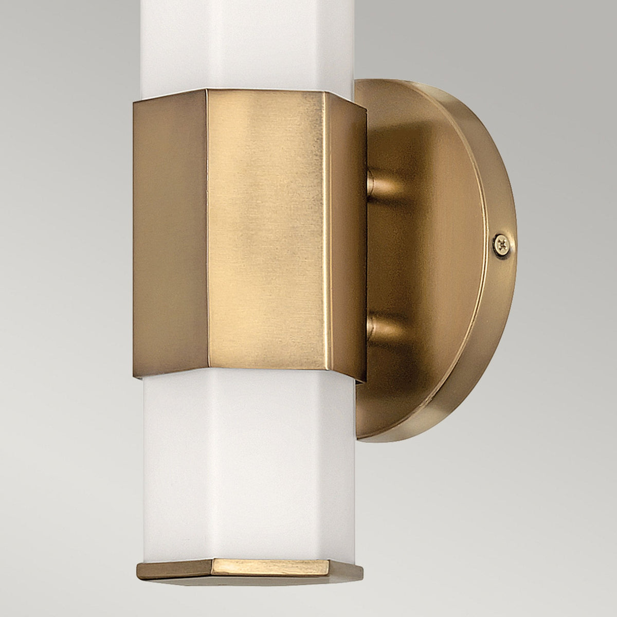 A close-up of the brass fixture and hexagonal white light of a wall light.
