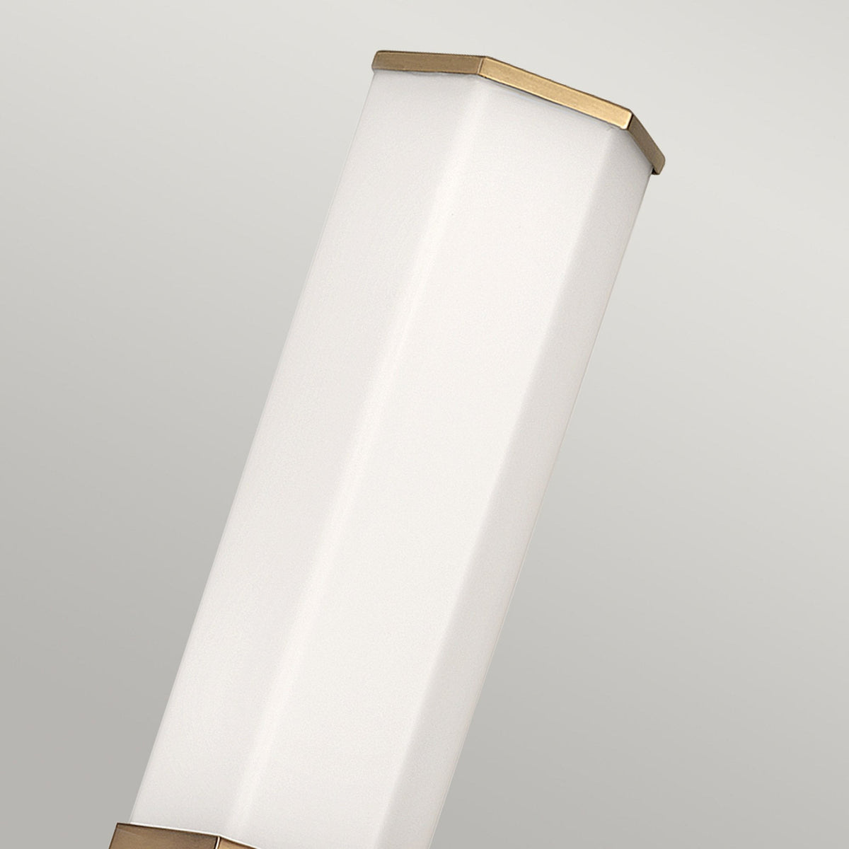A close-up of the hexagonal white light with brass trim from a wall light.