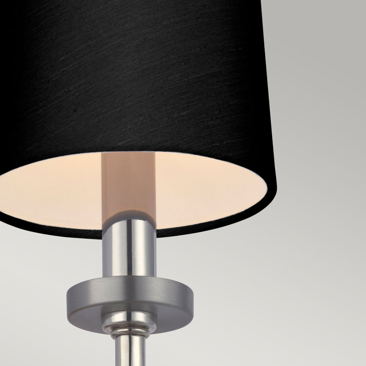 Close-up of the black conical shade and brushed nickel base of the wall light.