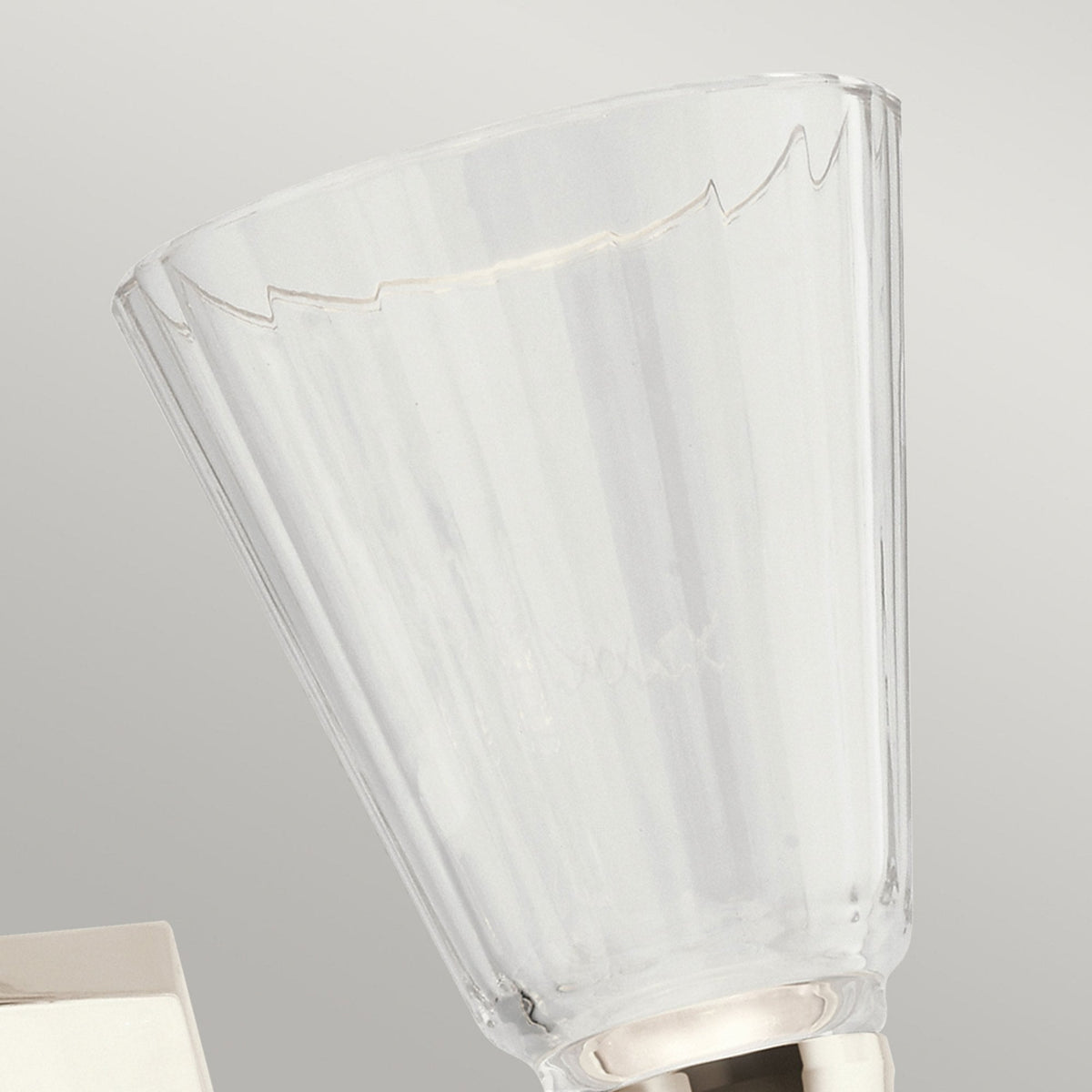 A close up of the fluted crystal shade on a two light nickel and crystal wall sconce.