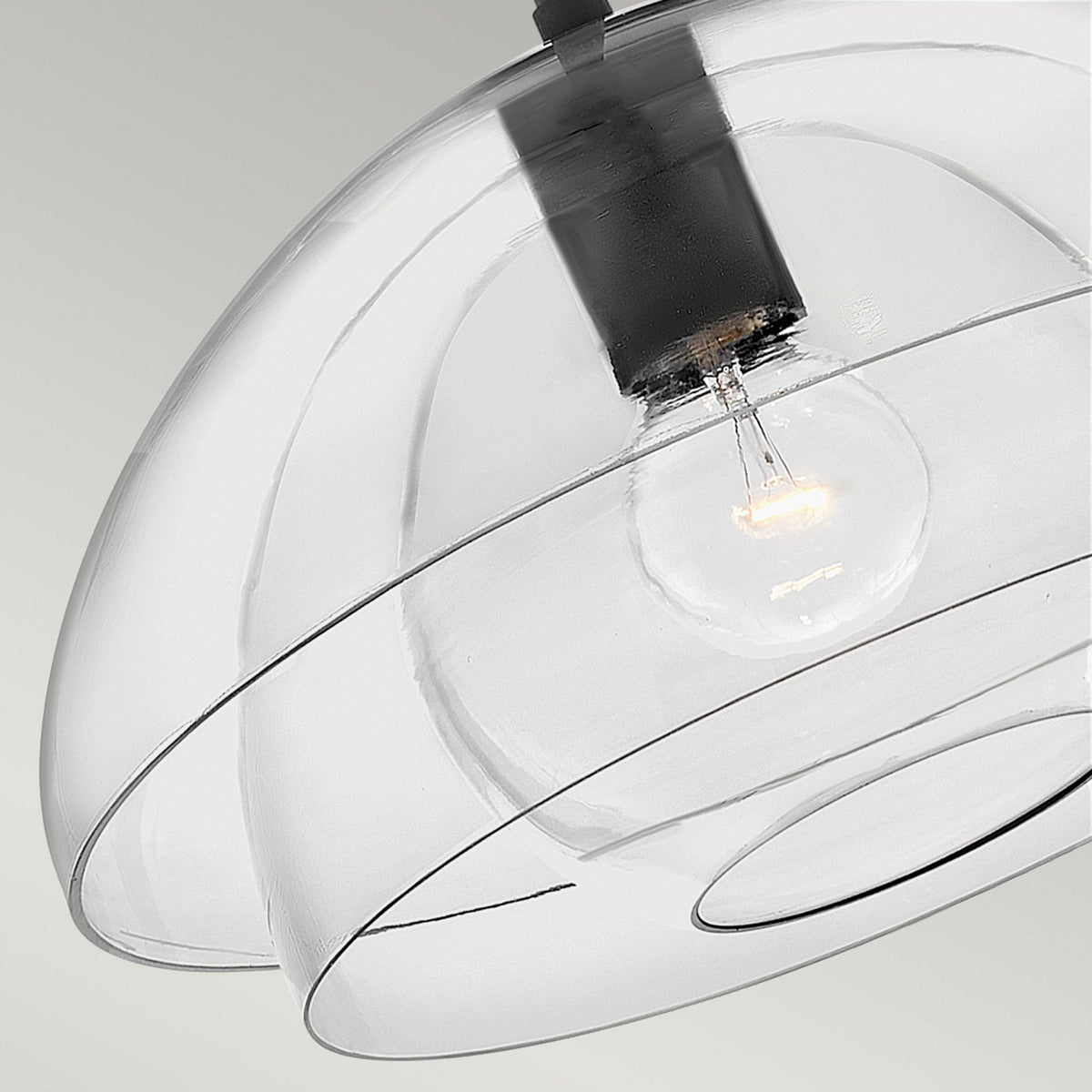 A close-up of a modern light with layered clear dome shades and a visible bulb.