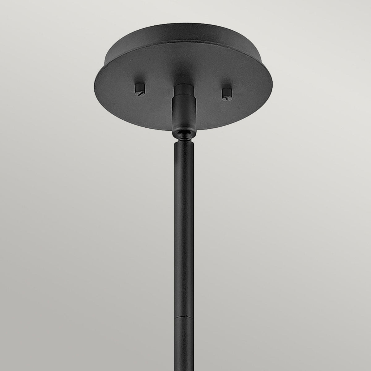 The ceiling mount of a black pendant light, showing a simple, round design.