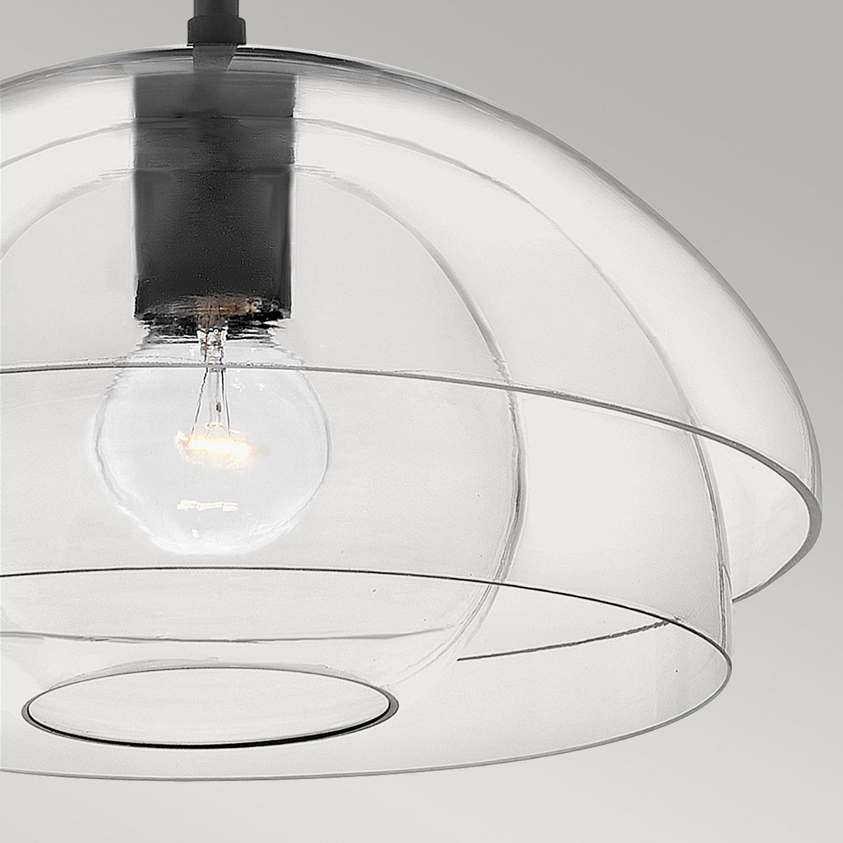 A detailed view of a modern light fixture with clear, concentric dome shades and an exposed bulb.
