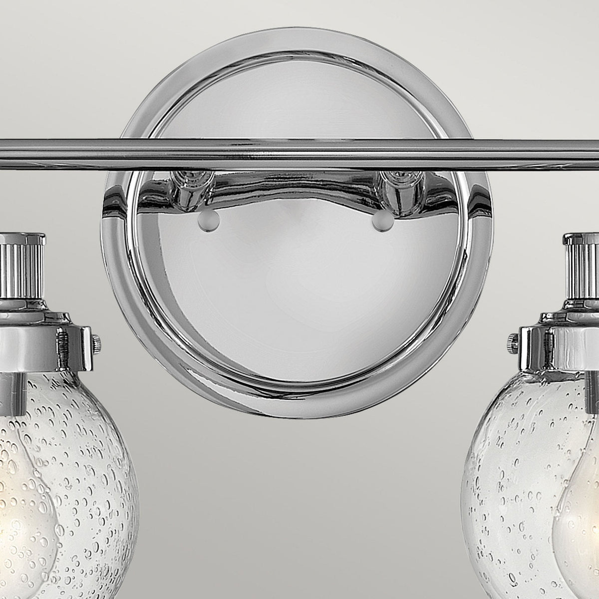 Close-up of the round chrome backplate of a two-light vanity fixture.
