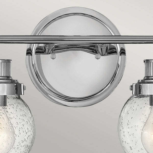 Close-up of the round chrome backplate of a two-light vanity fixture.