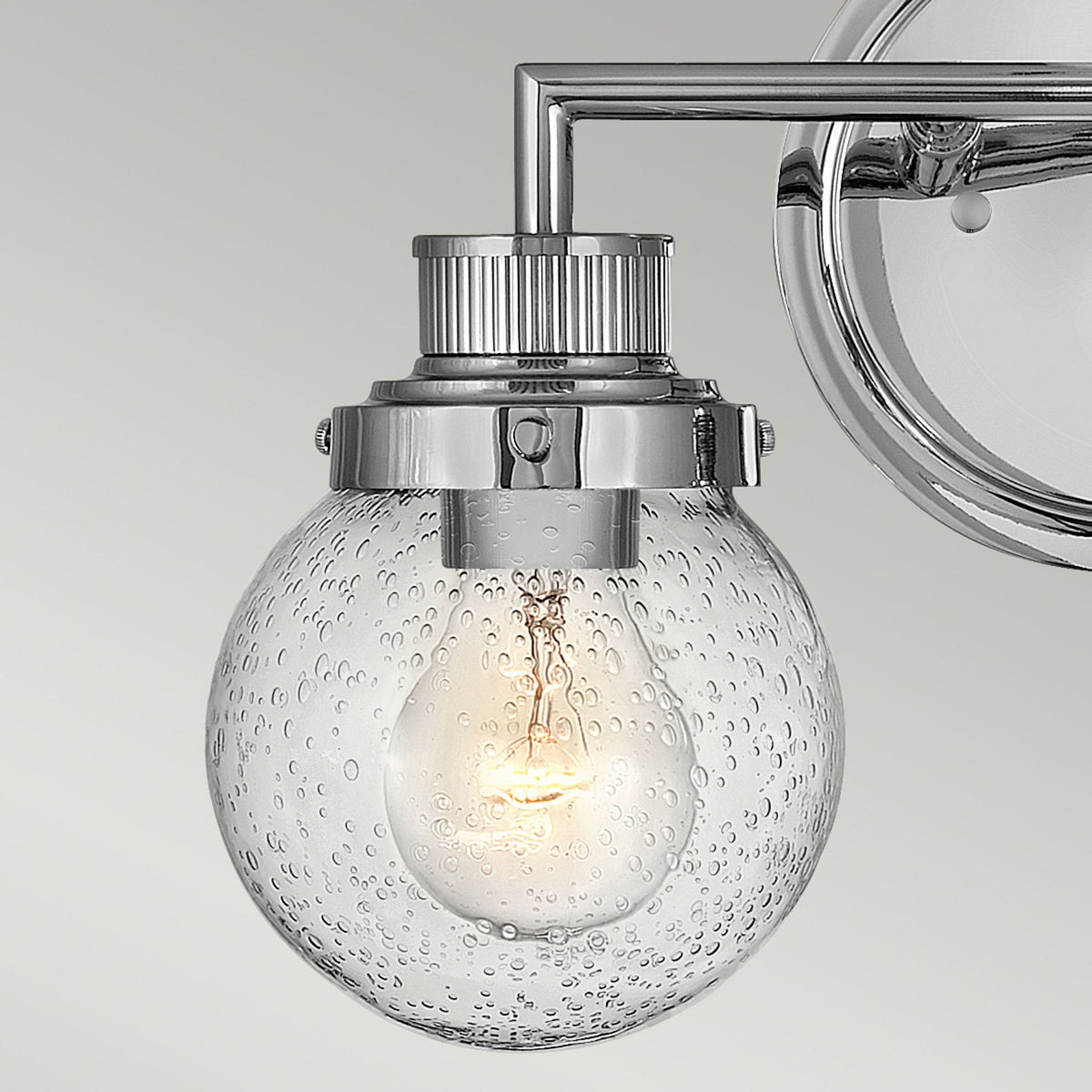 Detailed view of the chrome hardware connecting the glass shade to the fixture.