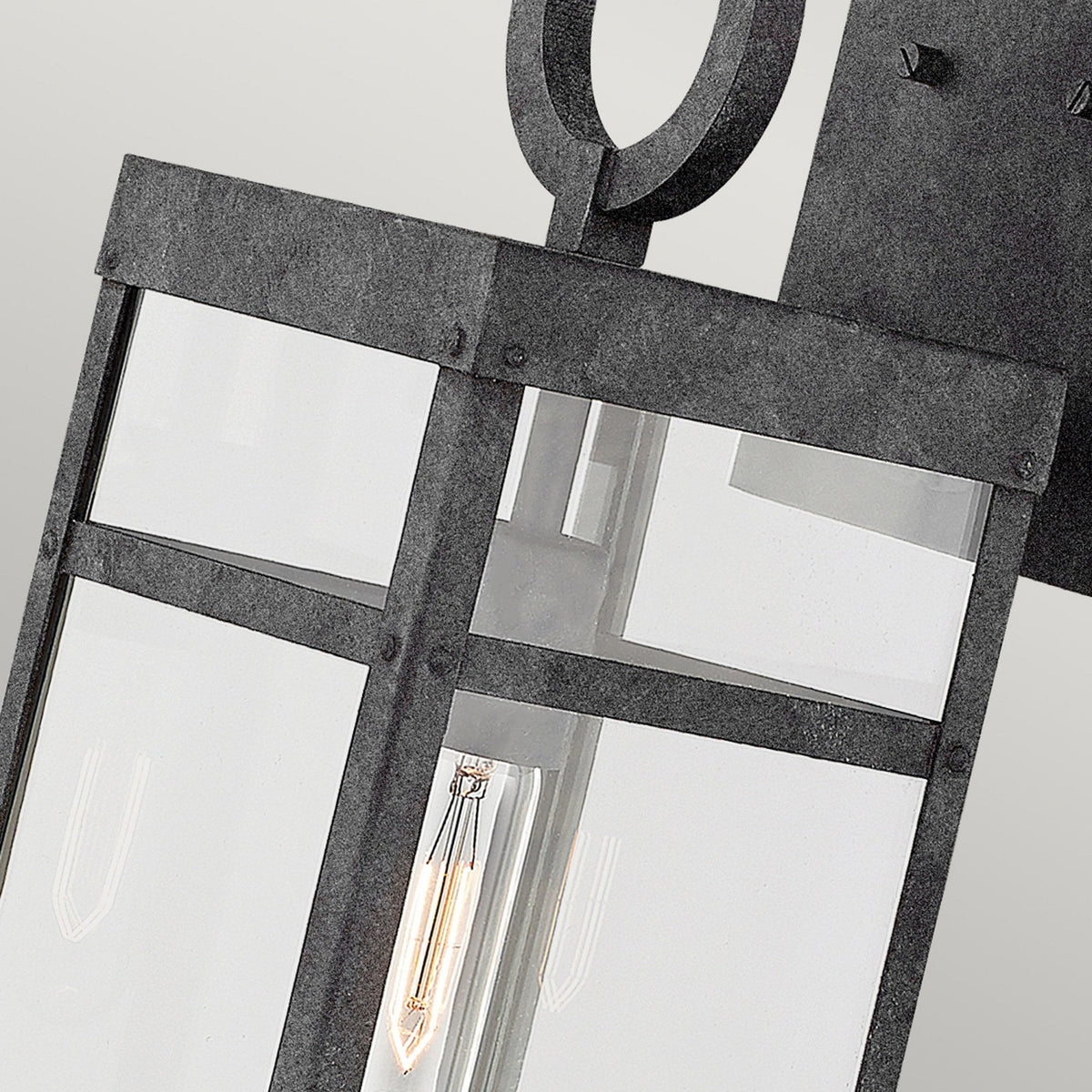 Detail of the top of the industrial wall light, highlighting the metal frame and Edison bulb.