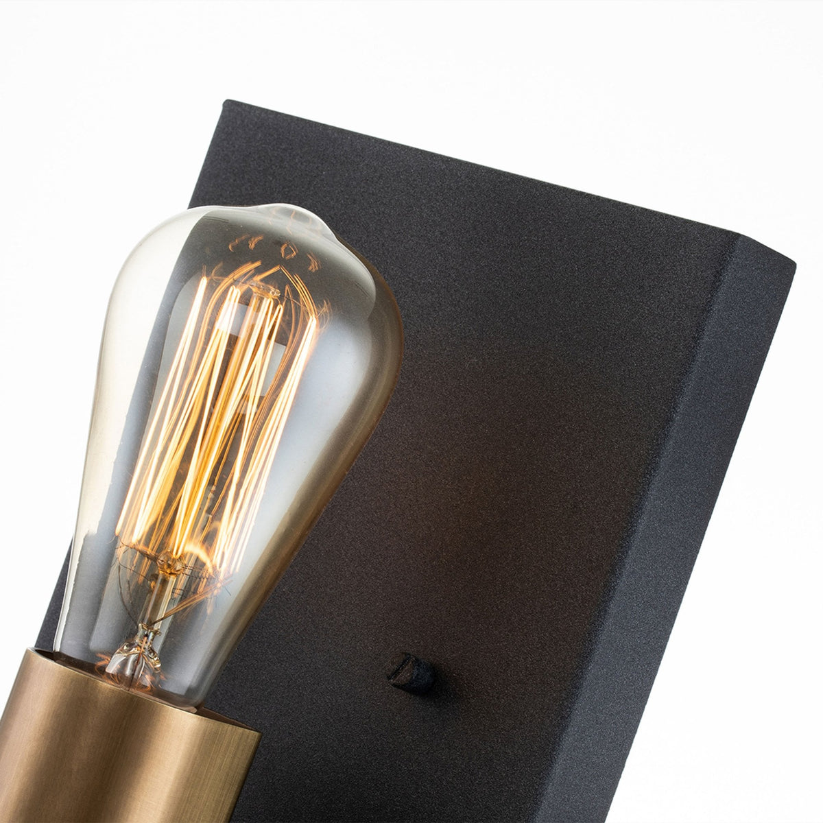 An angled view highlighting the black backplate and filament bulb of the wall light.