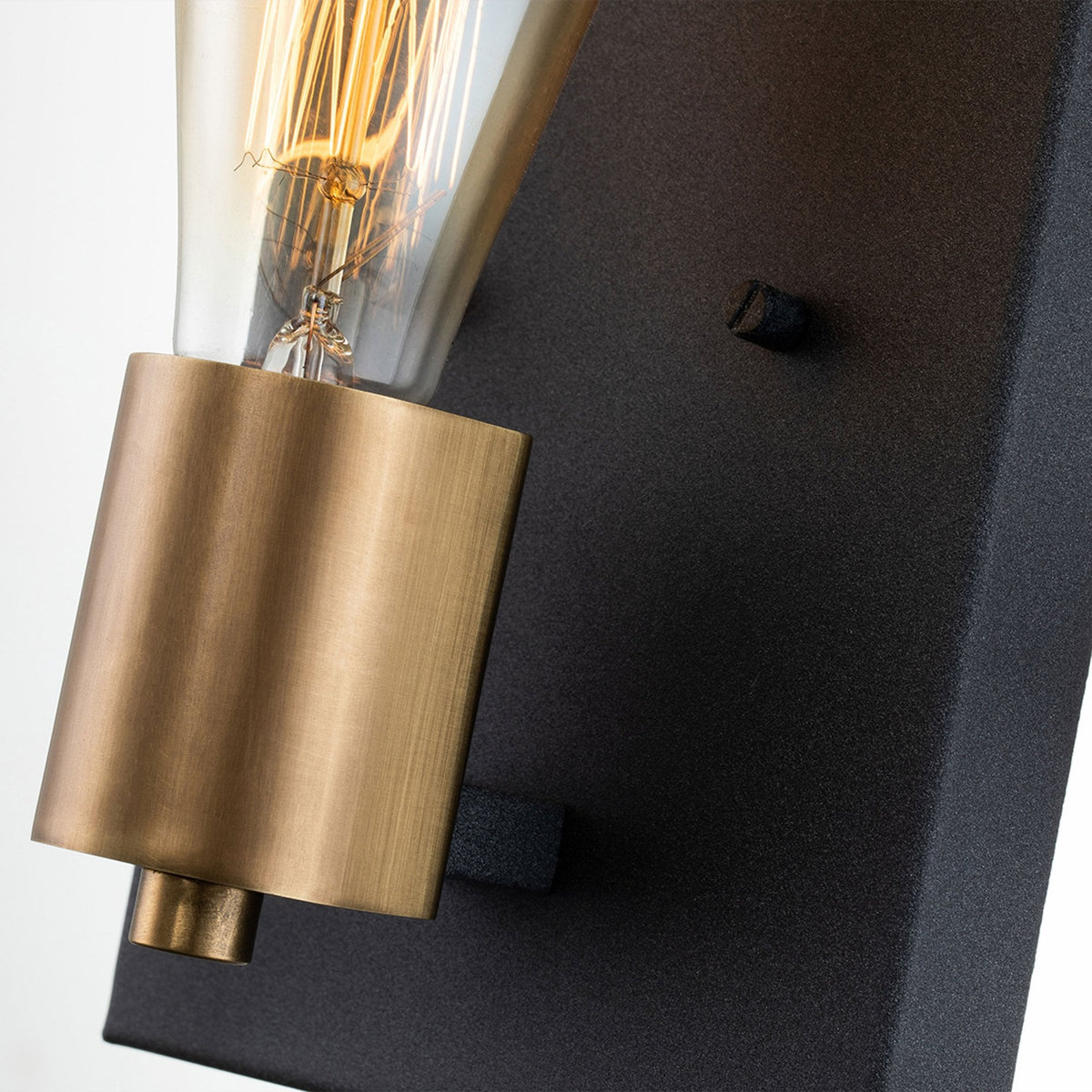 A close-up of the brass holder and black backplate showing texture and detail.